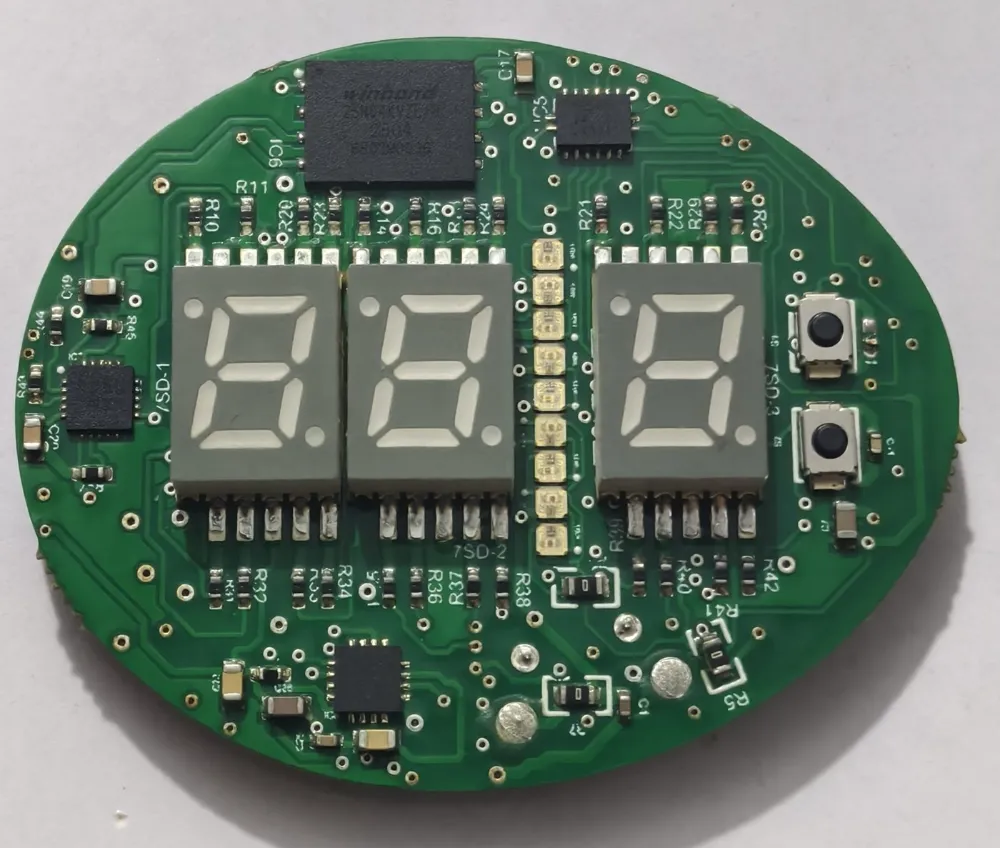 The finished round green circuit board, assembled with three seven segment displays, a Winbond flash memory, tactile buttons and LED bar